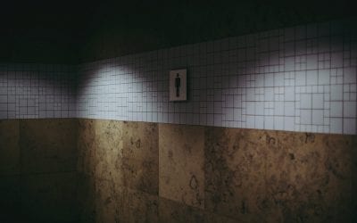 Photograph of a sign for men in a shadowy bathroom.