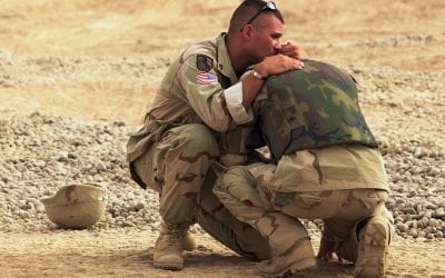 Photo of two soldiers embracing in Iraq after witnessing an explosion.