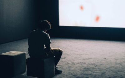 Photograph of a sad man regarding a blank screen.